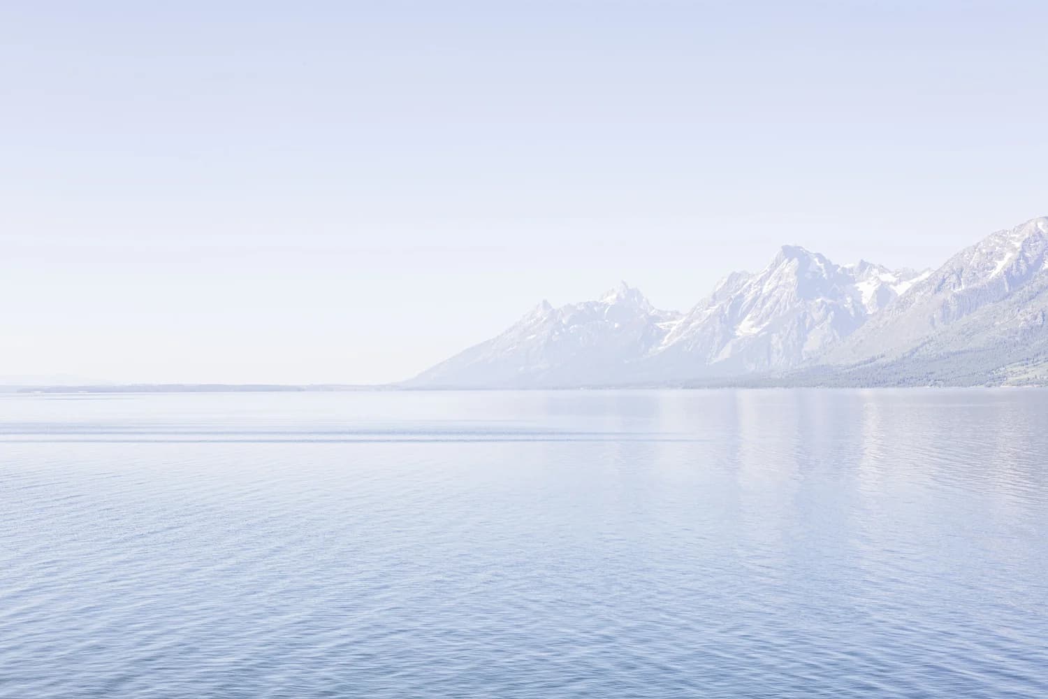Snow-capped peaks rising above a still alpine lake